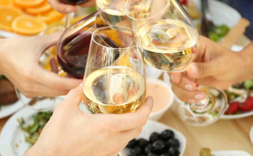 Vier Menschen stoßen mit Gläsern Weiß- und Rotwein an – ein Moment von Genuss, Geselligkeit und italienischem Lebensgefühl.
